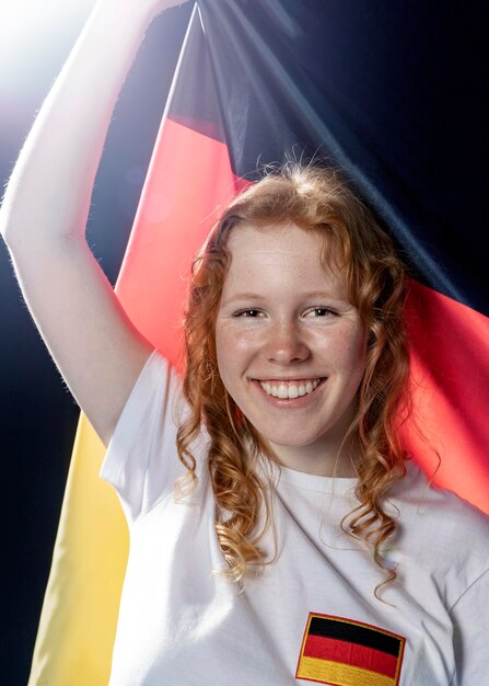 Vista frontale della donna sorridente che tiene bandiera tedesca