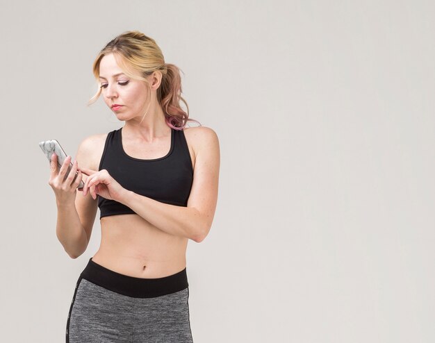 Vista frontale della donna sportiva che esamina il suo smartphone