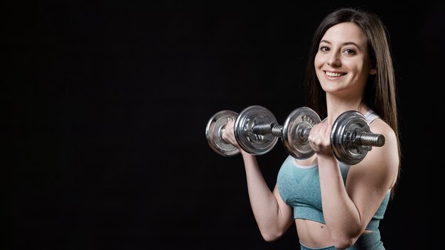 Vista frontale della donna sportiva con manubri