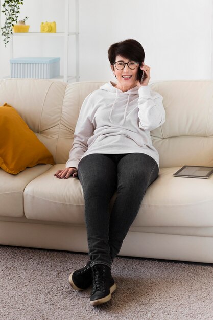 Vista frontale della donna sul sofà che parla sullo smartphone