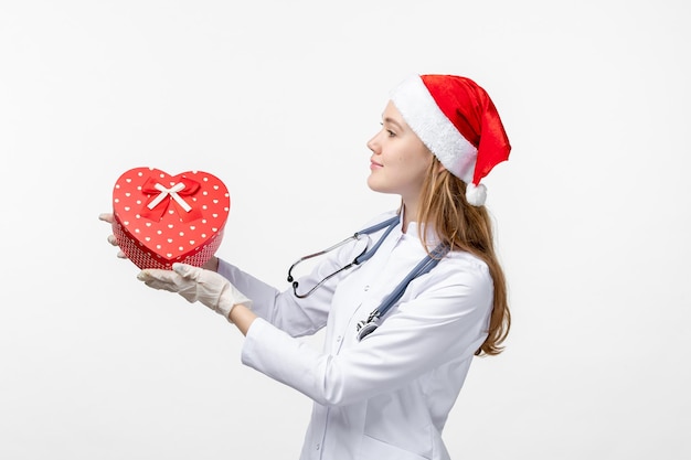 Vista frontale della dottoressa che tiene il regalo di festa sul muro bianco