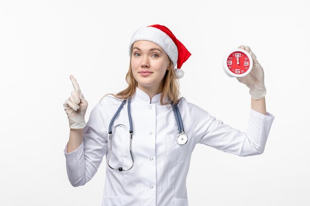 Vista frontale della dottoressa che tiene l'orologio sul muro bianco