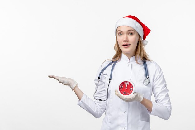 Vista frontale della dottoressa che tiene l'orologio sul muro bianco