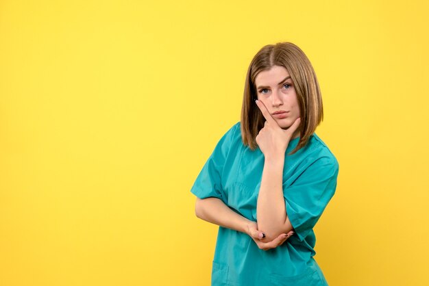 Vista frontale della dottoressa con espressione di pensiero sulla parete gialla