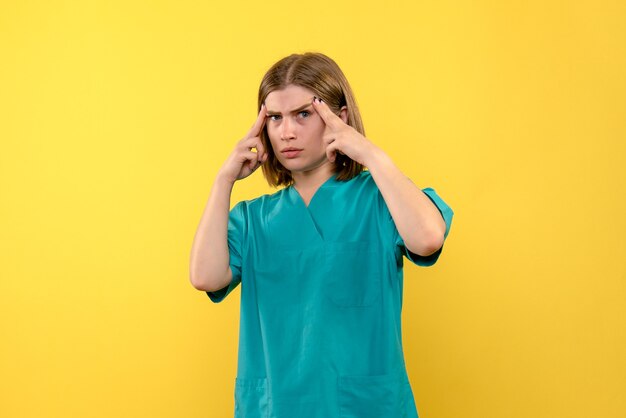 Vista frontale della dottoressa con espressione nervosa sulla parete gialla