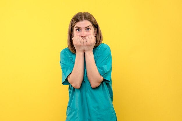 Vista frontale della dottoressa con espressione spaventata sulla parete gialla