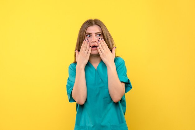 Vista frontale della dottoressa con la faccia spaventata sulla parete gialla