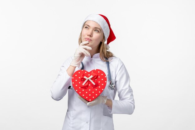 Vista frontale della dottoressa con regalo di festa sul muro bianco