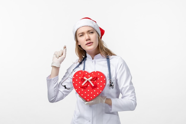 Vista frontale della dottoressa con regalo di festa sul muro bianco