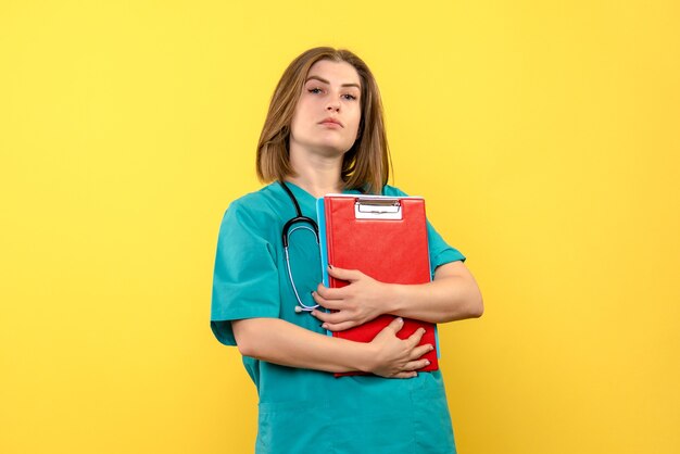 Vista frontale della dottoressa con tonometro e file sulla parete gialla