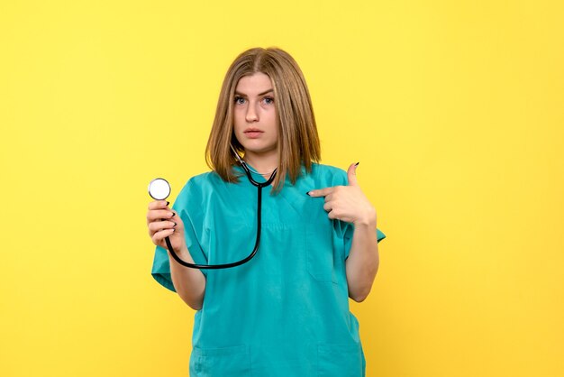 Vista frontale della dottoressa con tonometro sulla parete gialla