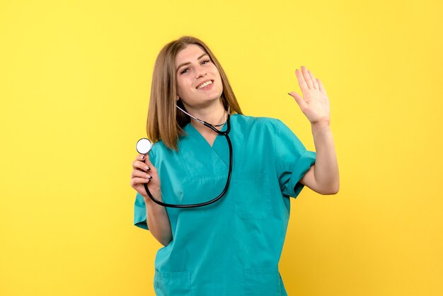 Vista frontale della dottoressa con tonometro sulla parete gialla