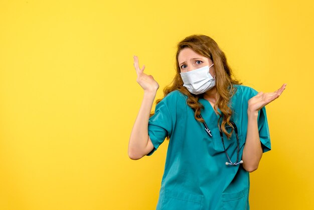 Vista frontale della dottoressa in maschera sulla parete gialla