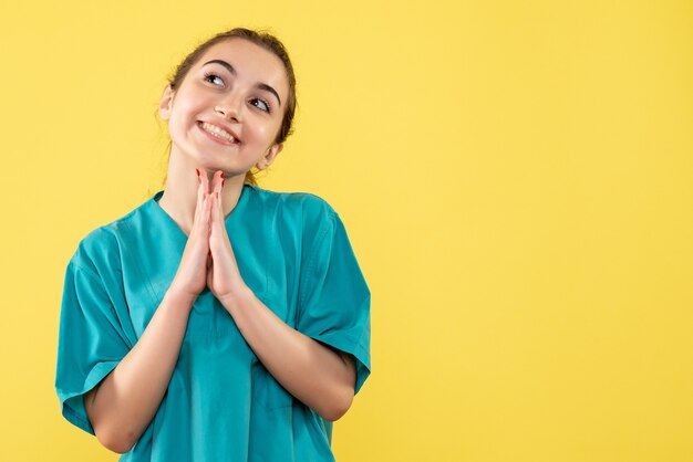 Vista frontale della dottoressa in tuta medica che sogna sulla parete gialla