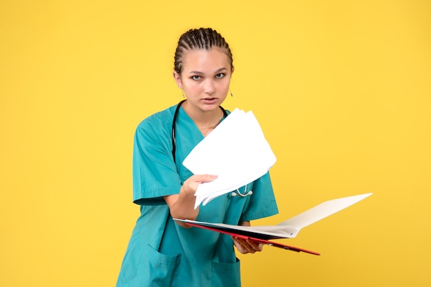 Vista frontale della dottoressa in tuta medica con analisi diverse sulla parete gialla