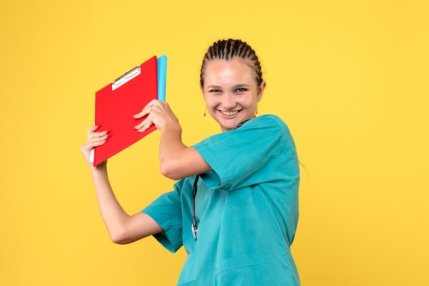 Vista frontale della dottoressa in tuta medica con analisi diverse sulla parete gialla