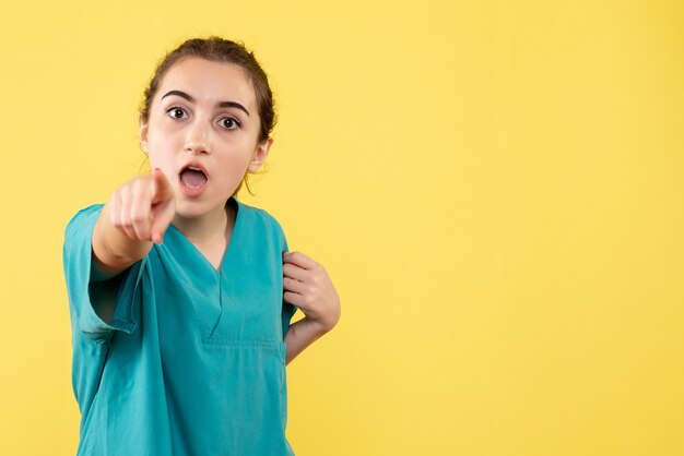 Vista frontale della dottoressa in tuta medica sulla parete gialla