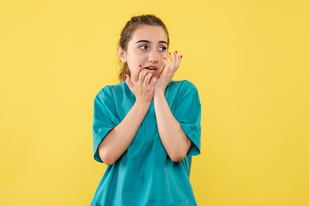 Vista frontale della dottoressa in tuta medica sulla parete gialla