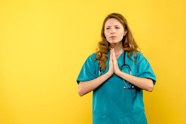 Vista frontale della dottoressa nella preghiera posa sulla parete gialla