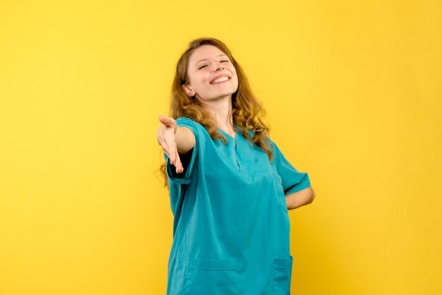 Vista frontale della dottoressa sorridente sulla parete gialla