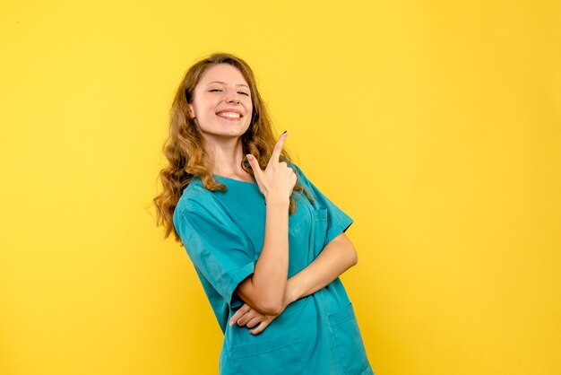 Vista frontale della dottoressa sorridente sulla parete gialla