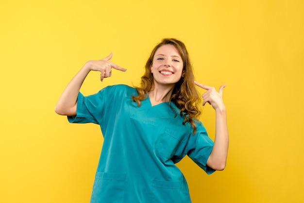 Vista frontale della dottoressa sorridente sulla parete gialla