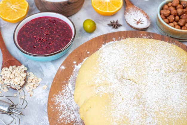 Vista frontale della farina di pasticceria cruda su tavola rotonda marmellata di nocciole uova kumquat farina d'avena su sfondo grigio