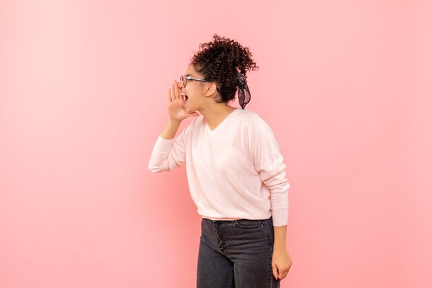 Vista frontale della femmina graziosa che chiama ad alta voce sul rosa