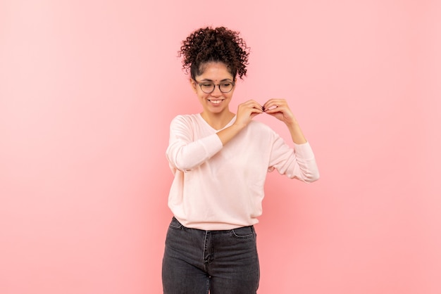 Vista frontale della femmina graziosa che sorride felicemente sul rosa