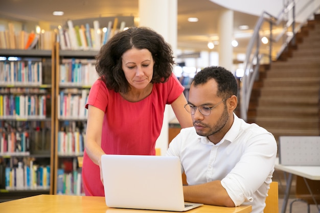 Vista frontale della gente concentrata che esamina insieme computer portatile