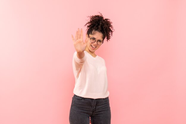 Vista frontale della giovane donna che chiede di fermarsi sulla parete rosa