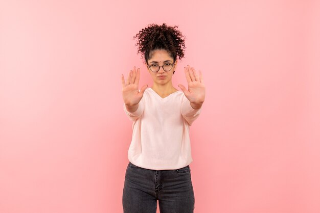 Vista frontale della giovane donna che chiede di fermarsi sulla parete rosa