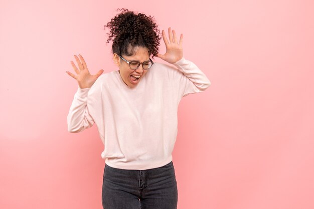 Vista frontale della giovane donna che grida sulla parete rosa