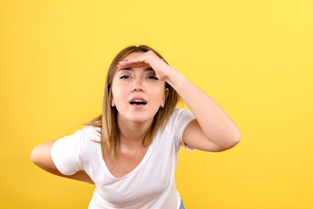 Vista frontale della giovane donna che guarda a distanza sulla parete gialla