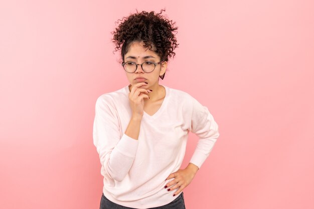 Vista frontale della giovane donna che pensa sulla parete rosa