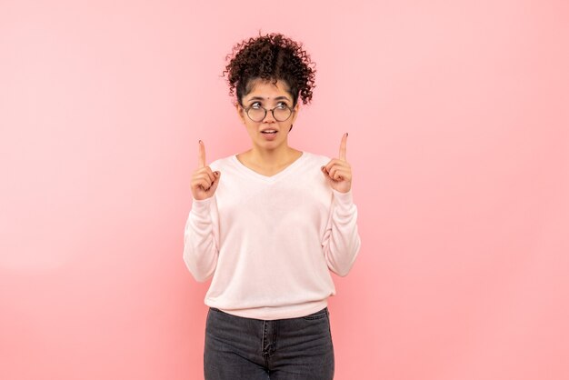 Vista frontale della giovane donna che pensa sulla parete rosa