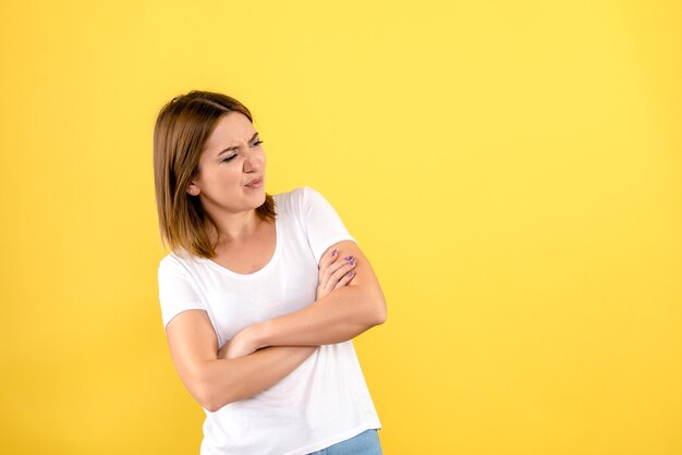 Vista frontale della giovane donna che posa appena sulla parete gialla