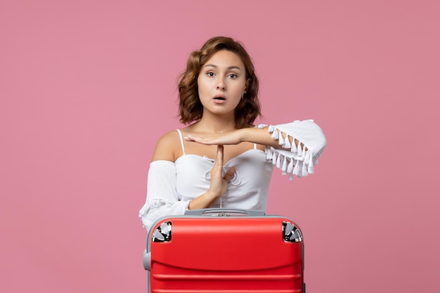 Vista frontale della giovane donna che posa con la borsa rossa delle vacanze sulla parete rosa