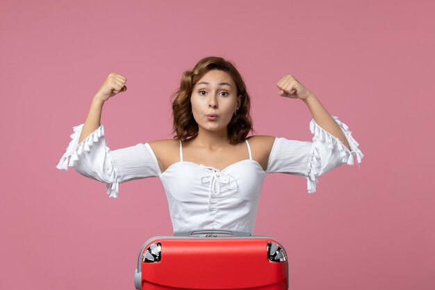 Vista frontale della giovane donna che posa emotivamente sulla parete rosa