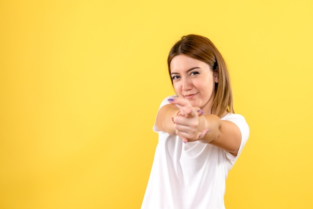 Vista frontale della giovane donna che punta sulla parete gialla