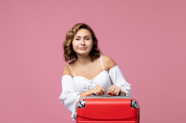 Vista frontale della giovane donna che si prepara per il viaggio estivo con borsa rossa sul muro rosa pink