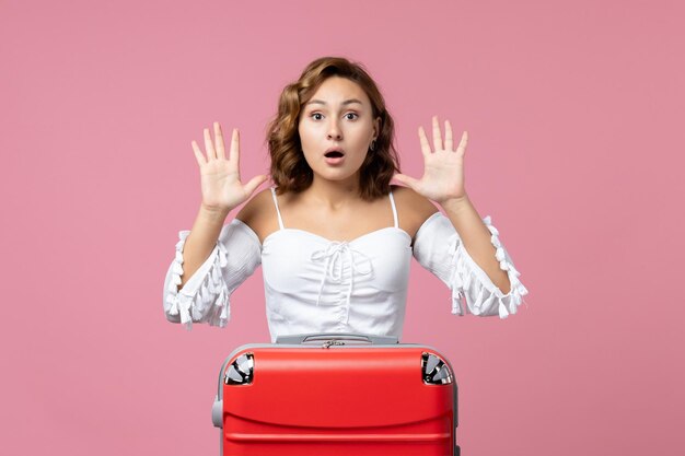 Vista frontale della giovane donna che si prepara per le vacanze con la borsa e posa sul pavimento rosa vacanza viaggio in mare modello viaggio colore