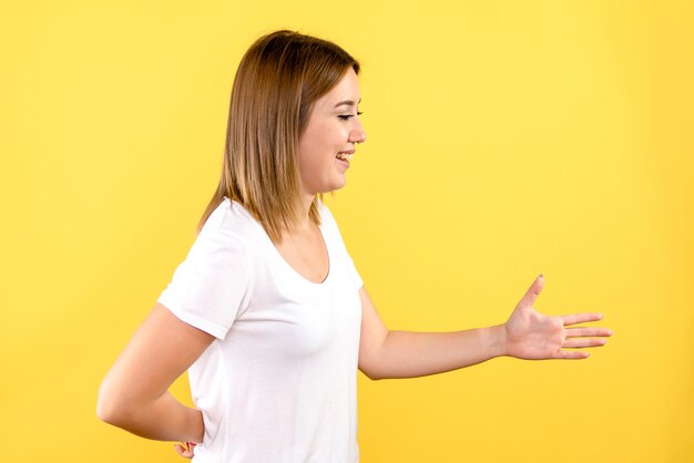 Vista frontale della giovane donna che stringe la mano a qualcuno sulla parete gialla