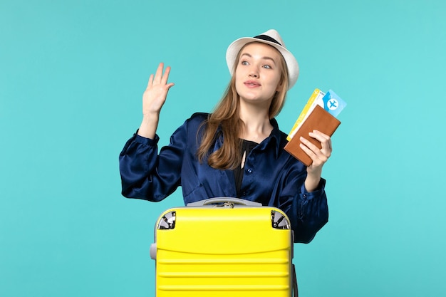 Vista frontale della giovane donna che tiene i biglietti e si prepara per il viaggio su sfondo azzurro viaggio mare vacanza viaggio viaggio aereo