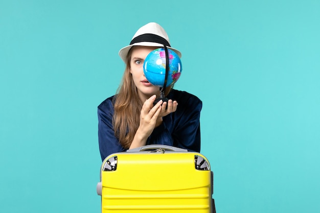 Vista frontale della giovane donna che tiene il globo e si prepara per la vacanza su sfondo blu femminile viaggio viaggio viaggio idrovolante vacanza