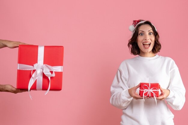 Vista frontale della giovane donna che tiene poco presente e non accetta il regalo dall'uomo sulla parete rosa