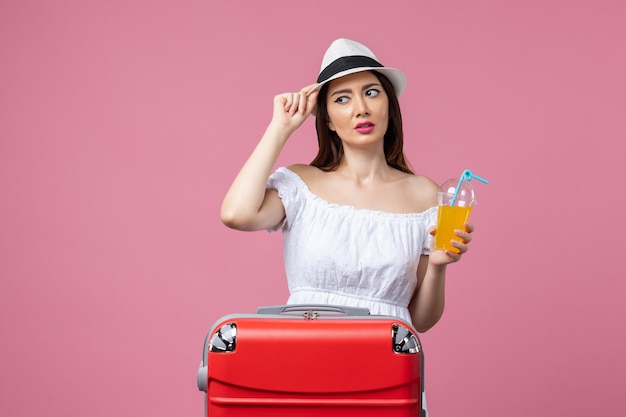 Vista frontale della giovane donna che tiene un cocktail durante le vacanze estive su un viaggio di viaggio estivo di calore di vacanza di parete rosa