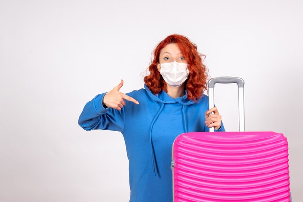 Vista frontale della giovane donna con borsa rosa sul muro bianco