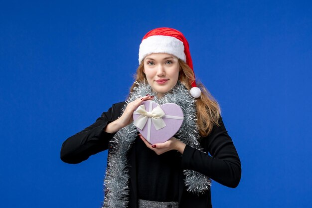 Vista frontale della giovane donna con il regalo di Capodanno sulla parete blu