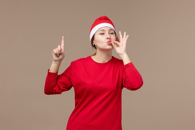 Vista frontale della giovane donna con il viso felice su marrone